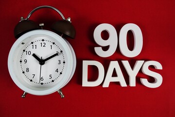 90 Days alphabet letters with alarm clock on red background