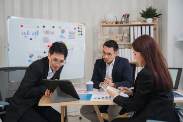 Business Meeting Strategy: A focused team of professionals collaborates in a modern office setting, analyzing data on a tablet and whiteboard.