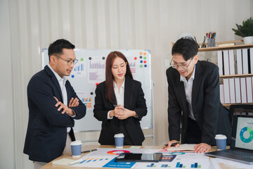 Business Professionals Collaborating: Three diverse business professionals engage in a serious discussion over a table covered in charts and graphs. The scene is set in a modern office.