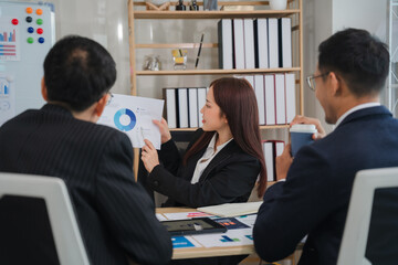 Business Meeting Presentation:  A focused businesswoman presents a compelling data chart to her colleagues during a productive office meeting.  The image conveys professionalism, collaboration.