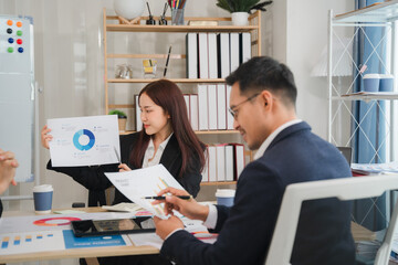 Business Presentation:  A focused team, diverse and professional, gathers around a table to analyze data, showcasing their dedication and collaboration. The image depicts a modern office setting.