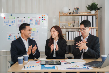 Business Team Celebrating Success: Three diverse colleagues in a modern office, celebrating a successful project or presentation with enthusiastic applause. The image conveys a sense of teamwork.