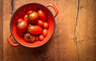 Tomatoes in a red colander on a wooden table, Finale Ligure, Italy
