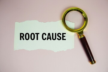 Root Cause text on paper torn with magnifying glass top view on pink background