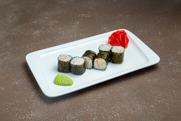 Japanese maki sushi with shrimp on plate with wasadi and ginger on grey background.
