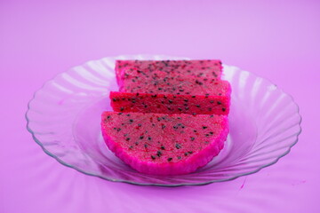 dragon fruit slices on a clear glass plate. dragon fruit slices isolated on a purple background