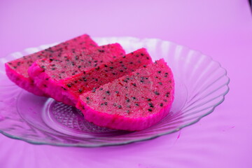 dragon fruit slices on a clear glass plate. dragon fruit slices isolated on a purple background