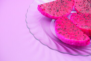 dragon fruit slices on a clear glass plate. dragon fruit slices isolated on a purple background