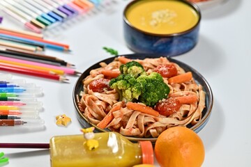 Colorful pasta with vegetables and art supplies.