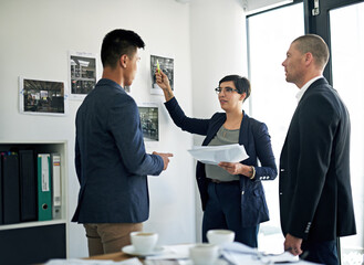 Feedback, meeting and training with business people in office together for coaching or development. Conversation, documents or review with employee man and woman group in corporate workplace