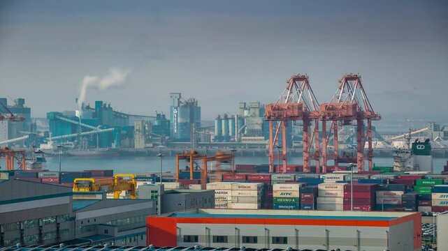 ASAN, SOUTH KOREA - OCTOBER 9, 2024: Busy shipping port with cranes and cargo containers by the waterfront showcasing industrial activity
