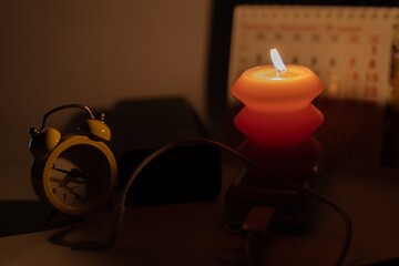 Burning candle and power banks near mechanical clock and calendar. Scheduled power outage due to...