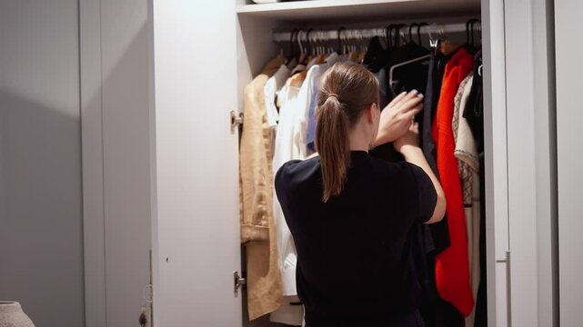 Closeup closet with casual clothes. Choosing her fashion outfit clothes in closet living room at house or store. Girl think what to wear casual shirt. Home wardrobe or clothing shop changing room.