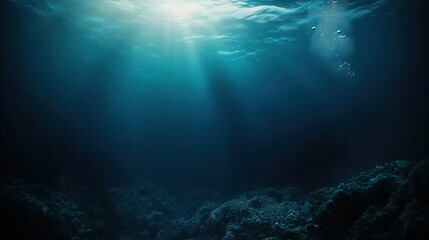 Obraz premium A serene underwater view featuring dark blue ocean water with soft light rays filtering through, bubbles rising towards the surface, and a mysterious deep-sea atmosphere. This immersive scene captures