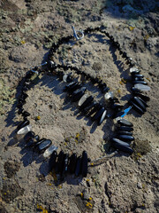 Black irregular beads gemstone necklace on ancient stone surface, covered with moss and lichen....