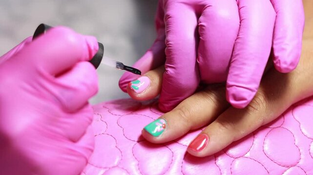 Unrecognizable woman painting colorful nails for a client at a manicure salon