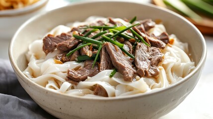 A bowl of noodles topped with beef and garnished with chives, served for a meal.