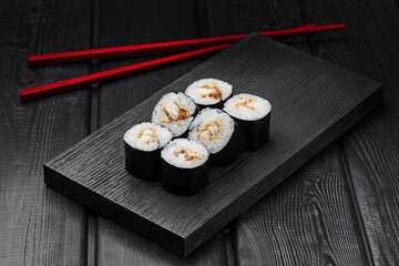 Japanese rolls, maki sushi with eel on black wooden background. © TrapezaStudio