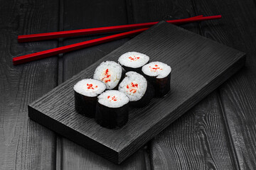 Japanese rolls, maki sushi with crab meat on a black wooden background.
