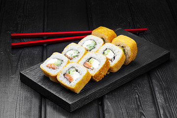 Japanese rolls, sushi in a pancake with fish, cucumber and cheese on a black wooden background.