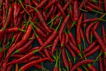 Top view of scattered red hot chili peppers, background.