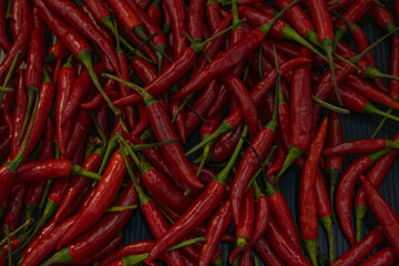 Top view of scattered red hot chili peppers, background.