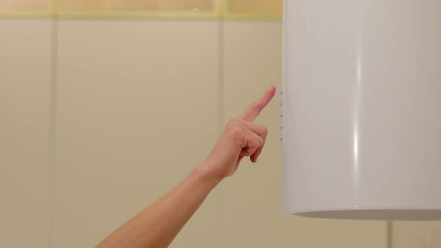 A woman presses buttons on the control panel of a modern exhaust ventilation system. Turning on the kitchen hood.