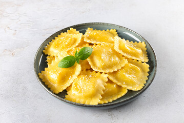 Ravioli with ricotta, gorgonzola, emmental and fresh basil on a gray background. Top view. 