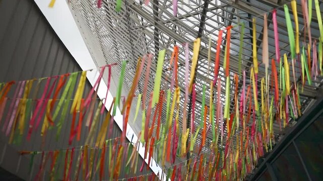 Colorful decorations in the wind in a cozy yard. Hanging multi-colored ribbons for a summer holiday. Yellow and blue ribbons sway in the wind. High quality FullHD footage
