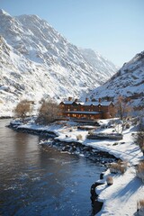 A stunning winter landscape featuring a cozy lodge surrounded by snow-covered mountains and a serene river.