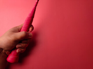 Closeup someone hand holding red racket badminton on a red background with copy and text space