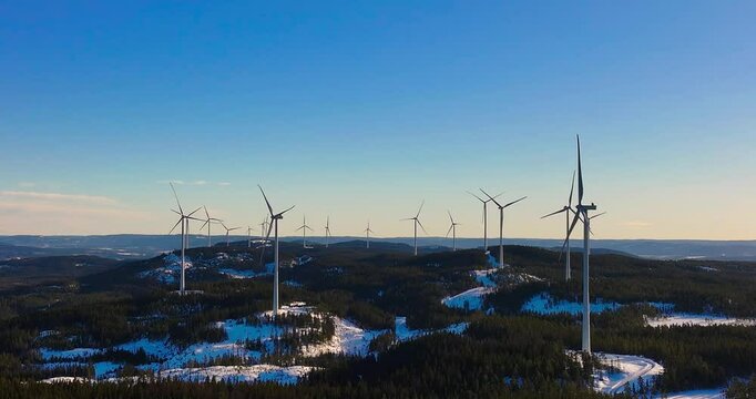 wind turbines on a snowy field against blue sky at sunrise at Odal Vindkraftverk wind farm in Norway