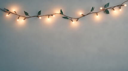 Warm Glowing String Lights with Green Leaves on a Grey Background