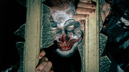 Grusliger Clown schaut aus  Fenster. 
