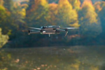 A drone is flying over a lake with trees in the background