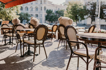 A restaurant with a lot of chairs and tables. There are two teddy bears on the tables.