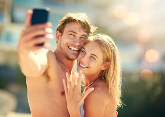Happy couple, selfie and engagement ring for love, marriage and celebrate together at beach outdoor. Man, woman and photo with wedding band to show commitment and proposal announcement on holiday