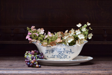 Autumn composition of flowers and grape  in vintage sauceboat