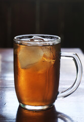 Glass of sweet iced tea on table with blur background