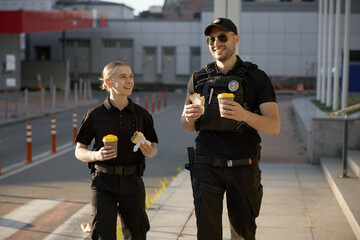 Happy smiling male and female patrol police officers enjoying lunch break