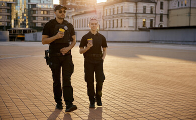 Obraz premium Happy smiling male and female patrol police officers enjoying lunch break