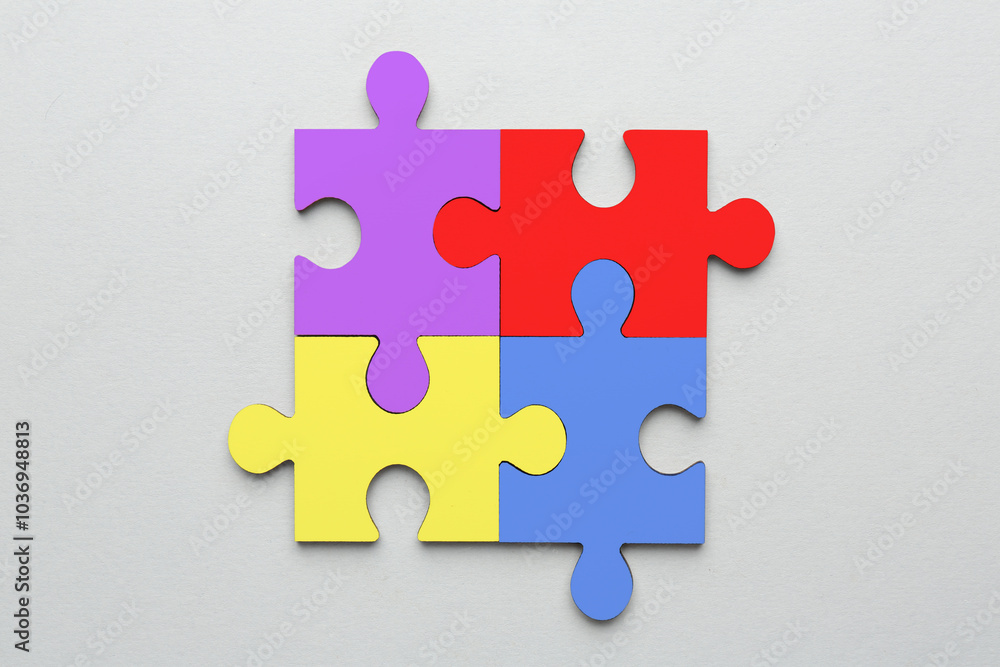 Sticker Four colorful puzzle pieces on light grey background, top view. Symbol of autism