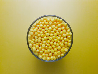 Yellow masterbatch granules in shot glass, isolated on yellow background,color pigment carrier...
