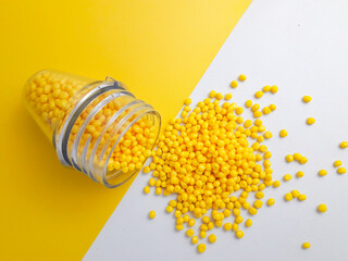 Yellow masterbatch granules spilled over a yellow and white background, a polymer that carries...