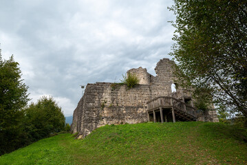 The medieval castle of Solimbergo, fraction of Sequals in Friuli, at the top of a hill that you can reach hiking in autumn. We see a wooden staircase with its ledge and over us a dramatic cloudy sky.