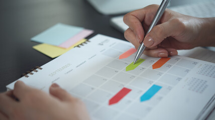 Closeup, woman hand writing on calendar event planner to set timetable organize schedule, event...