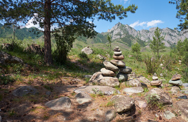 Stone pyramid under pine tree in Altai mountains.