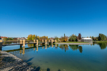 Obraz premium A magnificent green landscape with a river and a bridge on a clear sunny day.