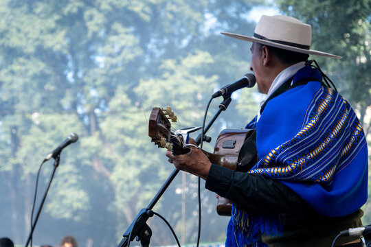 Gaucho argentino con sombrero y poncho azul tocando la guitarra y cantando folklore