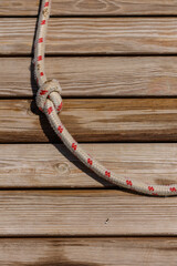 Obraz premium A close-up view of a taut rope with red markings coiled around wooden planks, bathed in warm sunlight on a tranquil afternoon